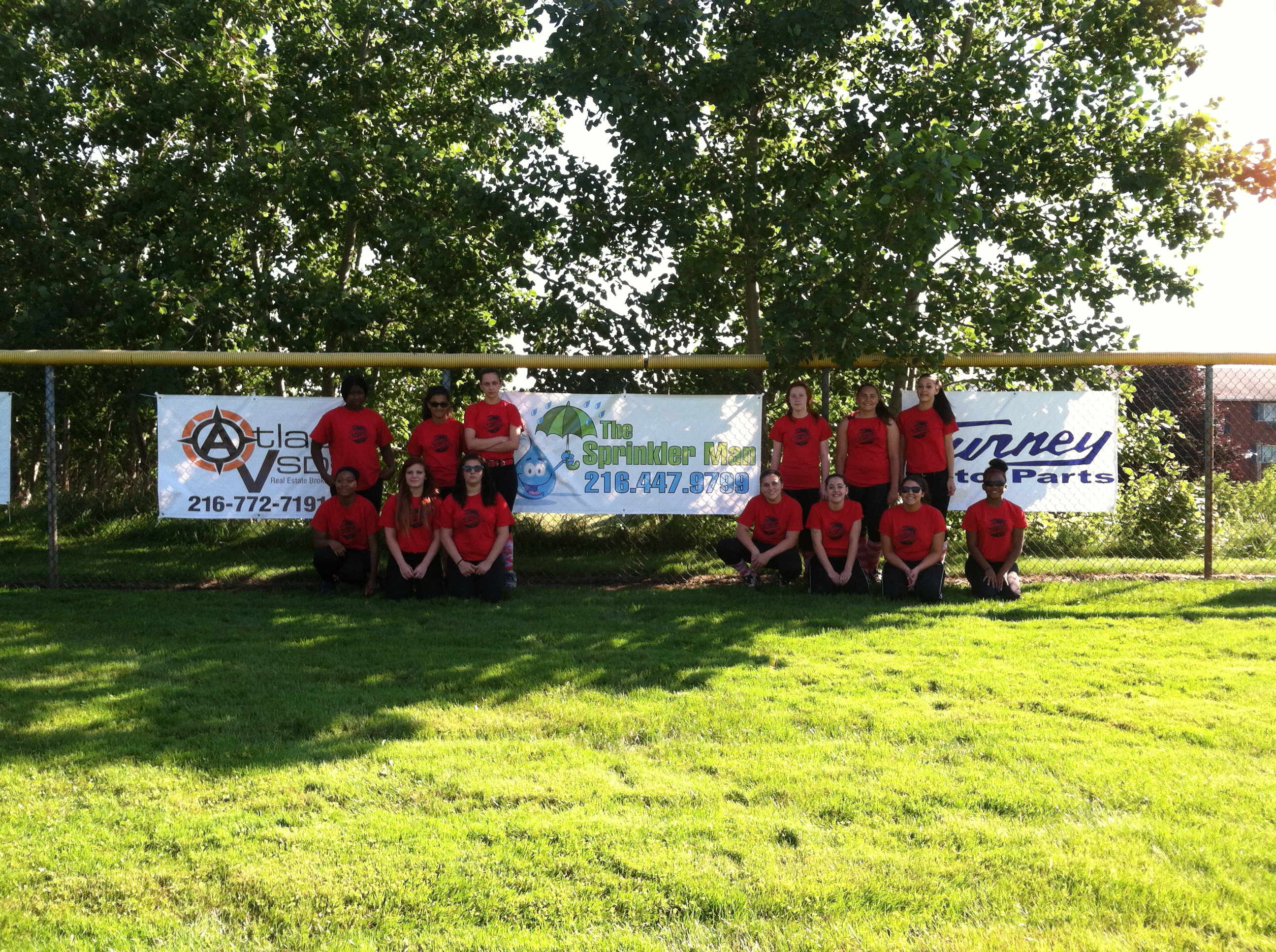 Team photo of the Sprinkler Man sponsored Garfield Girls Angels Softball Team in red uniforms standing proudly together